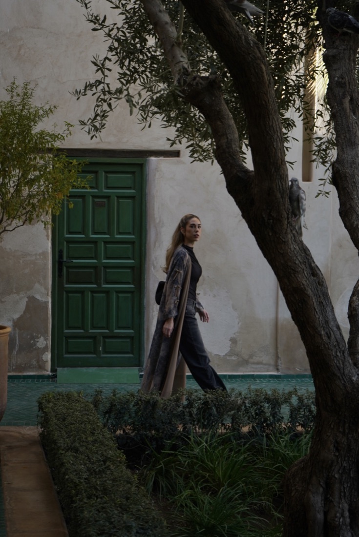 Woman walking past a green door in a Marrakech garden