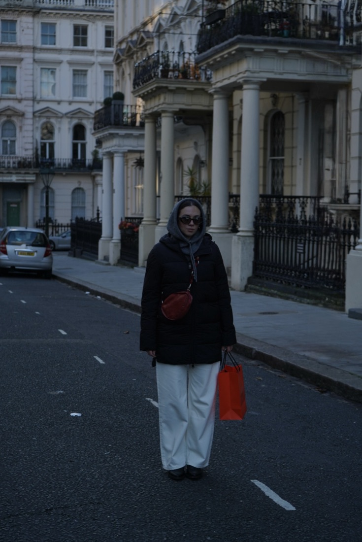 Woman with an orange shopping bag standing in a white stucco street